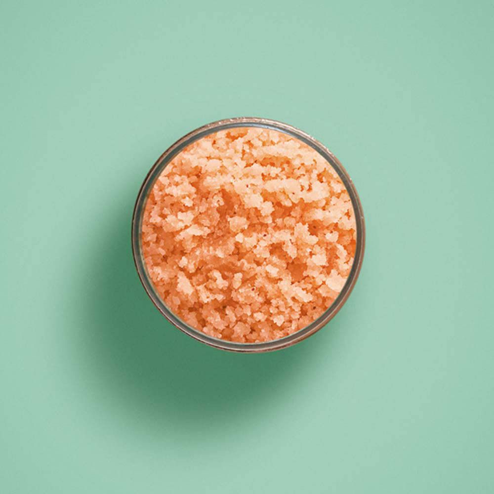 Vue de dessus du gommage. Produit orangé dans un récipient.
