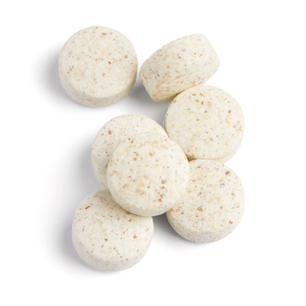 Sieben runde, beige Tabletten. Oberansicht. Tabletten mit sichtbaren Partikeln.