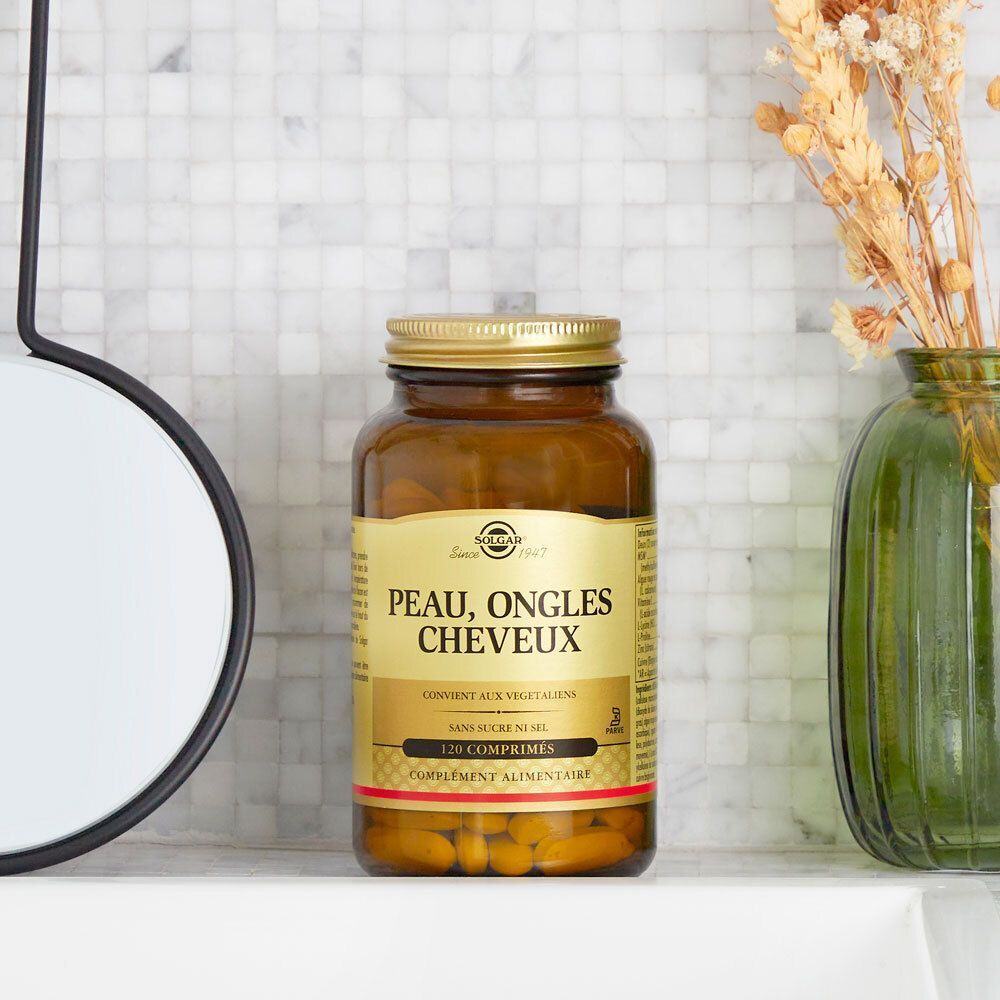 Eine Flasche Solgar Skin, Nails and Hair Formula. Braune Glasflasche mit goldenem Deckel. Steht auf einer weißen Oberfläche.