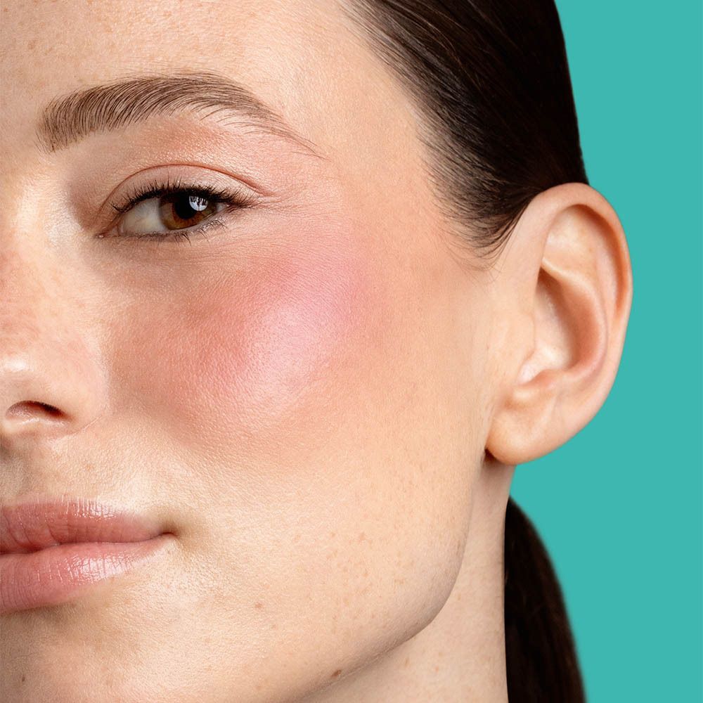 Visage de femme. Fard à joues sur la joue. Teint. Fond vert.