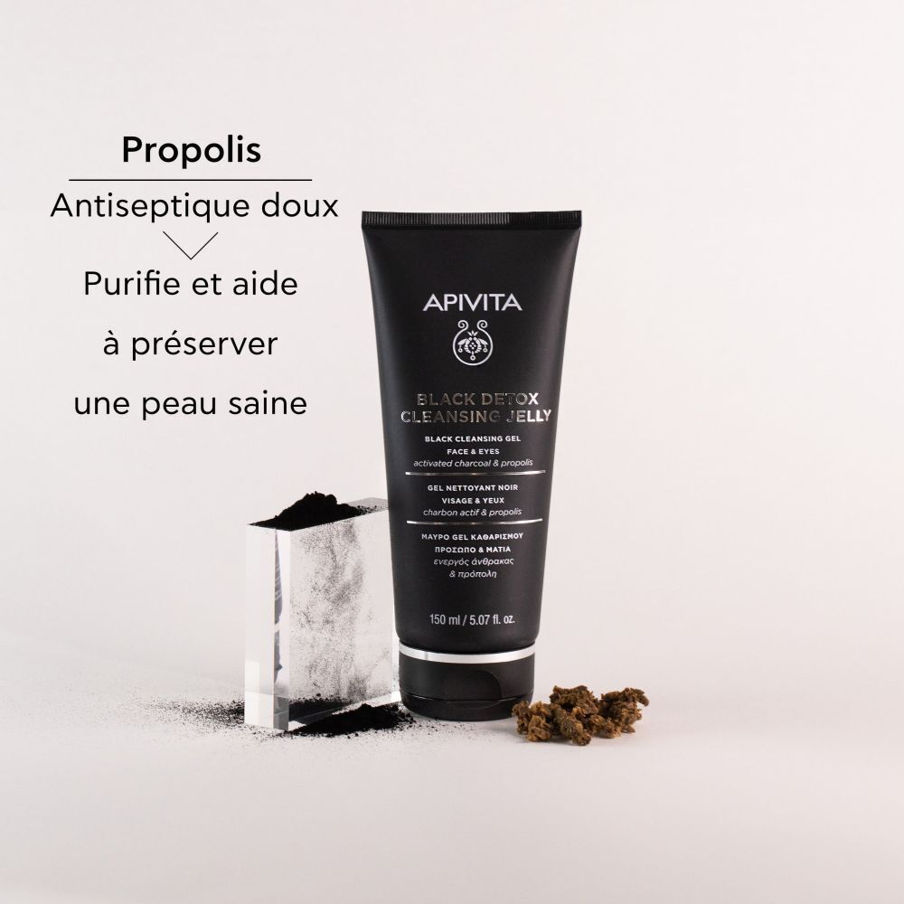 Un tube de gel nettoyant APIVITA Black Detox, à côté de charbon actif et de propolis. Texte: Purifie et aide à préserver une peau saine.