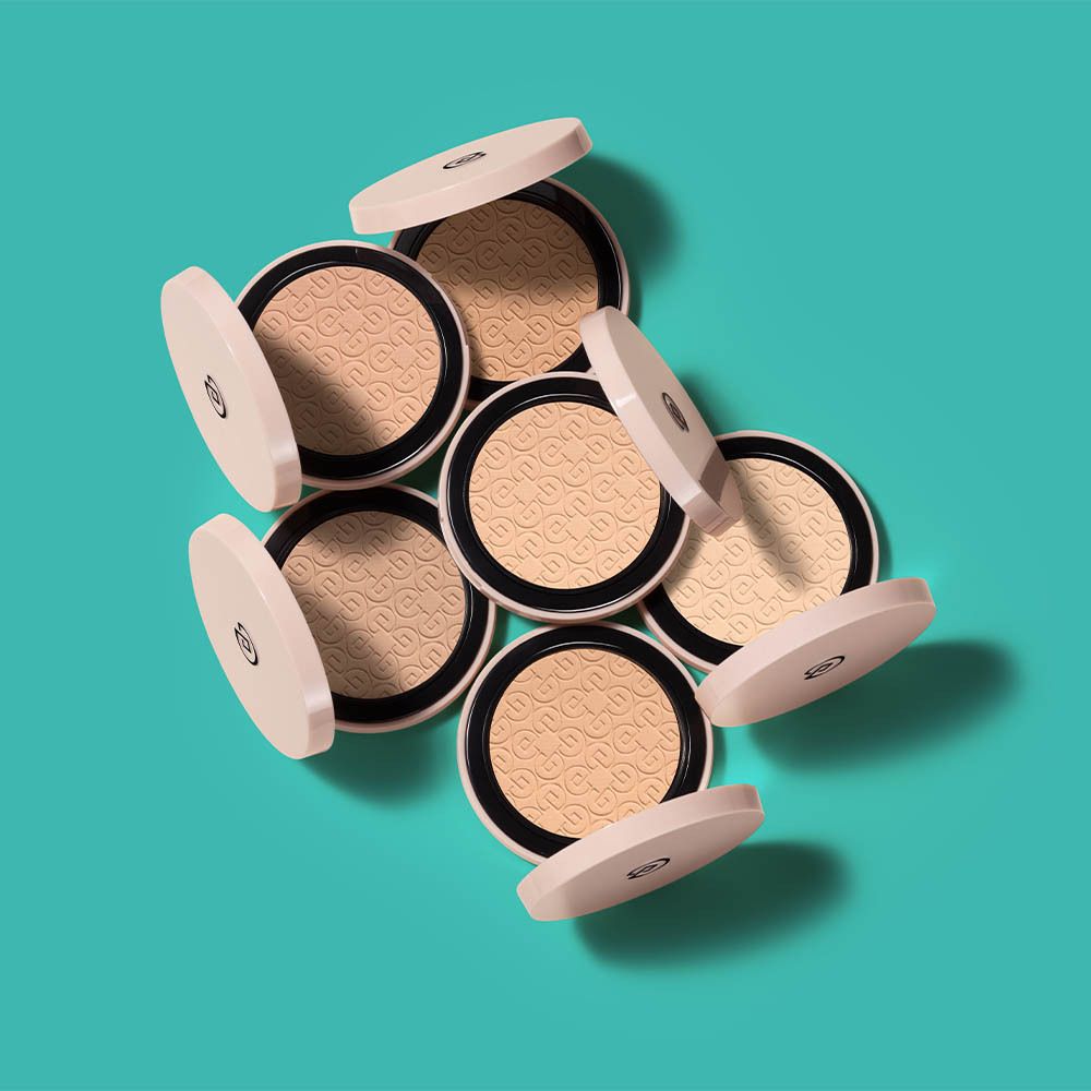 Plusieurs poudres compactes ouvertes. Poudre beige, couvercles roses.