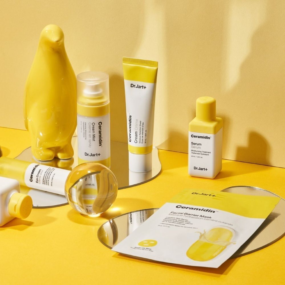 Fond jaune avec produits Dr.Jart+ Ceramidin. Comprend: masque, crème, sérum, brume et décoration.