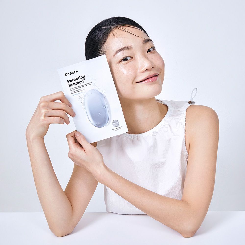 Une femme tient un masque Dr.Jart+ Porecting Solution. Le masque est dans un emballage blanc avec le nom du produit.