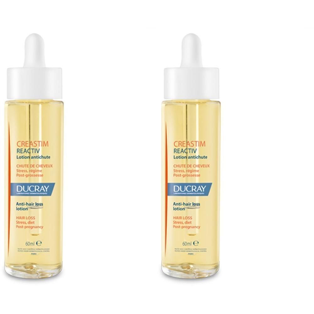 Zwei Flaschen DUCRAY Creastim Reactiv Lotion. Gelbe Flüssigkeit in Glasflaschen mit weißem Deckel und Pipette. Beschriftung.