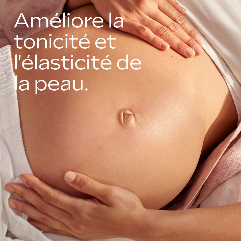 Gros plan sur le ventre d'une femme enceinte, huilé. Des mains massent doucement. Texte : 'Améliore la tonicité et l'élasticité de la peau.'