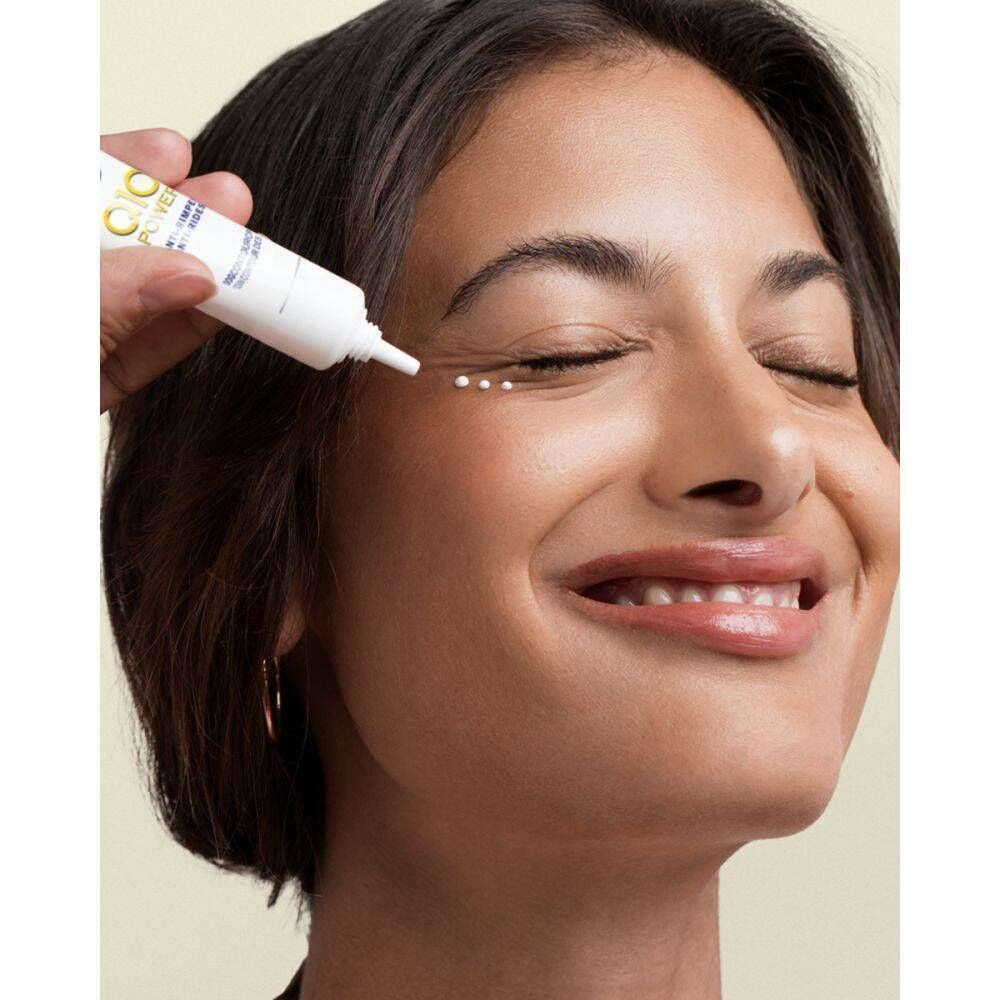 Frau mit geschlossenen Augen, Produkt wird aufgetragen. Weiße Tube mit blauem und gelbem Logo. Text: Q10 Power, Anti-Falten, Augenkonturcreme.
