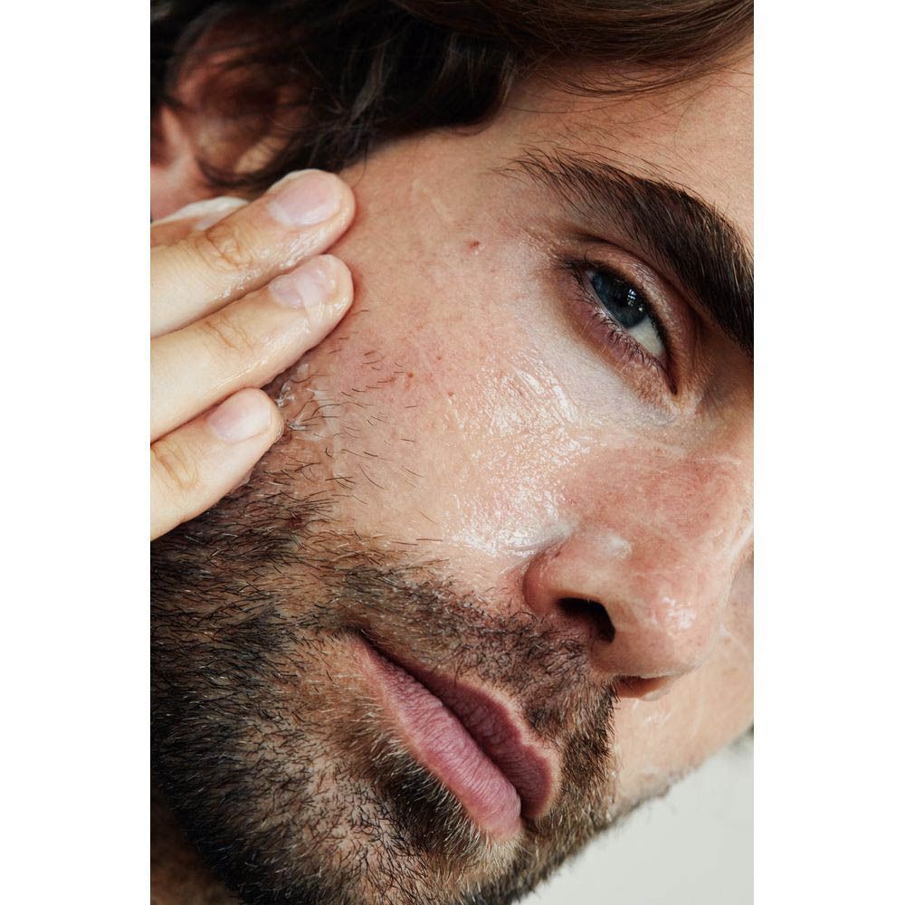 Homme appliquant de la crème sur son visage. Gros plan, peau couverte de crème.