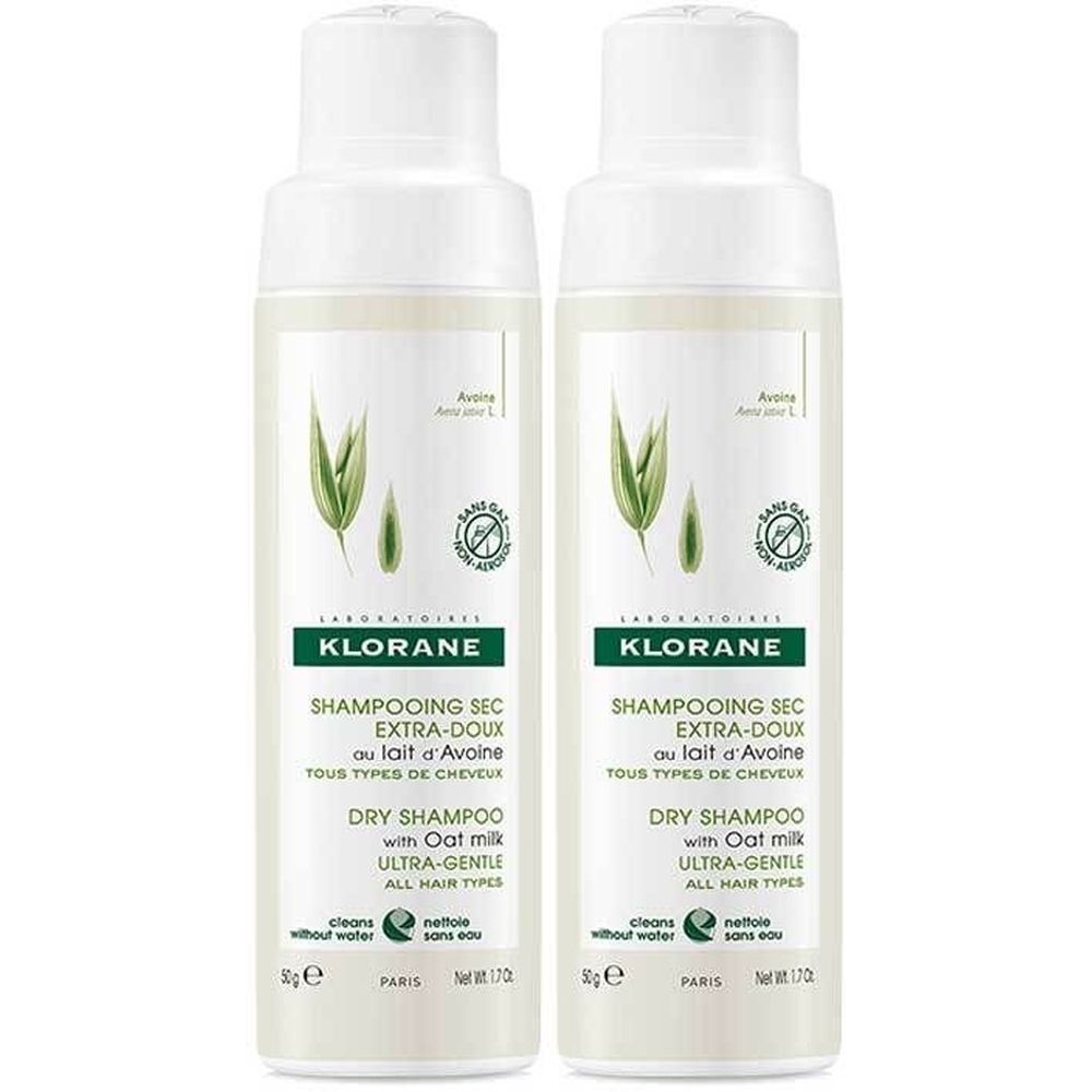 Deux flacons blancs. Inscription: KLORANE, Shampooing sec extra-doux au lait d'avoine. Étiquettes vertes et blanches avec logo et texte.