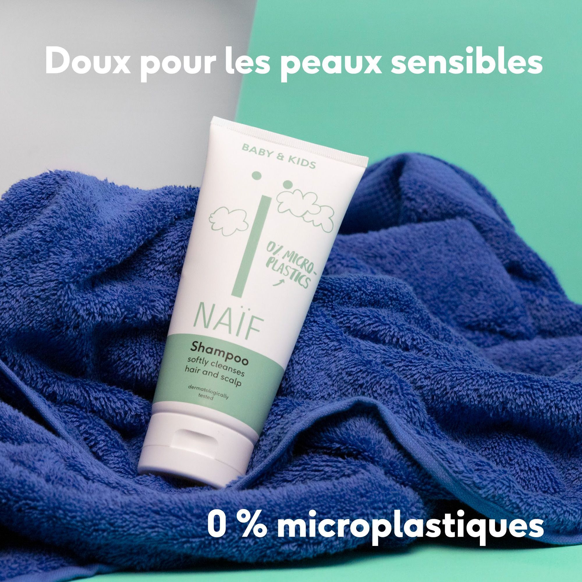 Naïf Babyshampoo-Tube auf blauem Handtuch, 0% Mikroplastik.