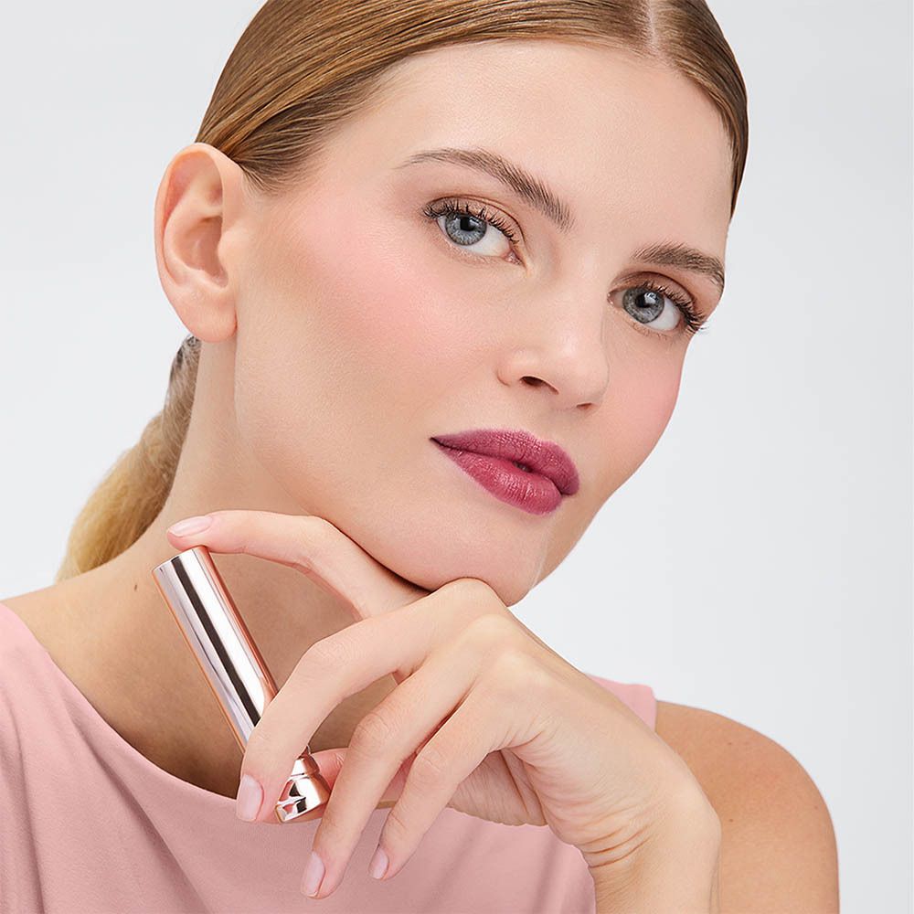Femme avec rouge à lèvres. Rouge à lèvres appliqué sur les lèvres. Haut rose, fond clair.