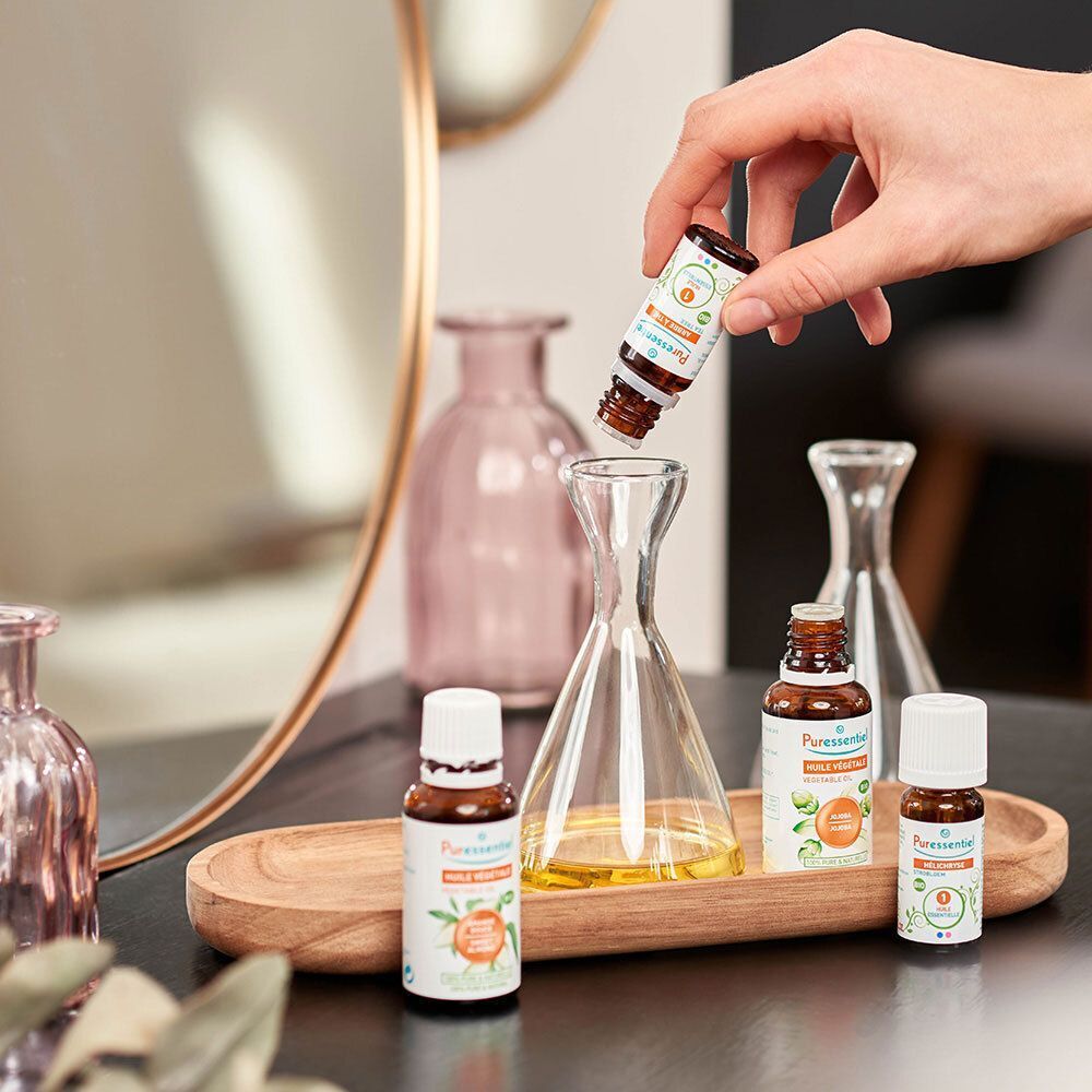 Main ajoutant une huile essentielle Puressentiel Lavande Bio dans un flacon en verre.