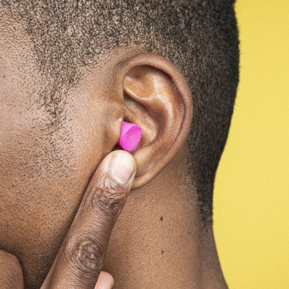 Ein Mann setzt einen rosa blox® Schaumstoff-Ohrstöpsel, klein, ein.