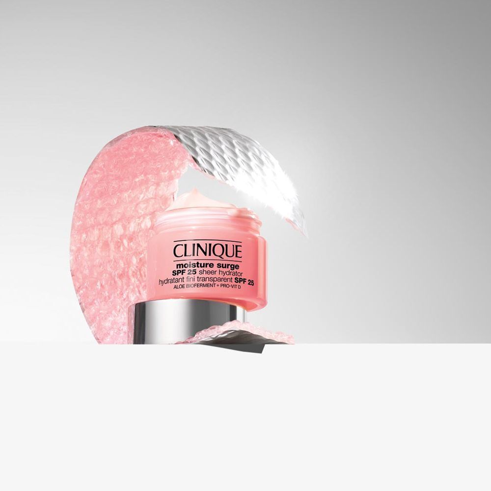 Ein Clinique Moisture Surge SPF 25 Sheer Hydrator Tiegel, umgeben von rosa Material.