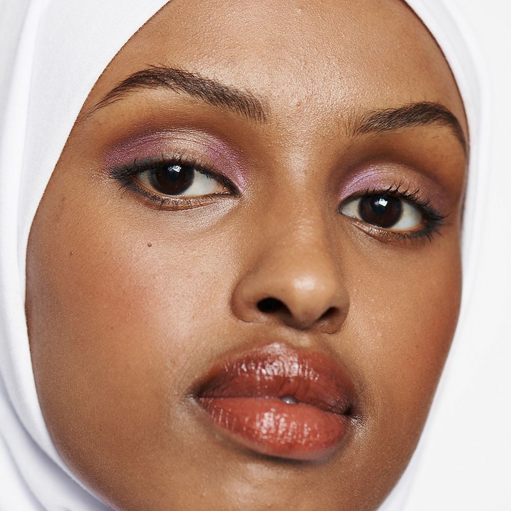 Porträt einer Frau mit geschminkten Augen und Lippen, trägt einen weißen Hijab.