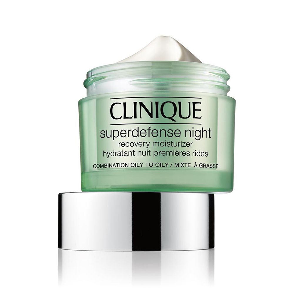 Un pot ouvert de crème de nuit Clinique Superdefense avec son couvercle argenté à côté.