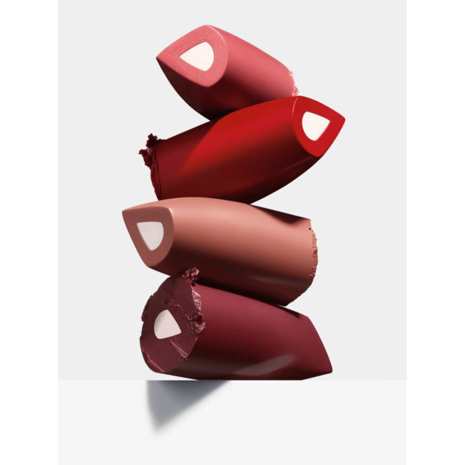 Quatre rouges à lèvres empilés verticalement dans différentes nuances de rouge, montrant la surface coupée.