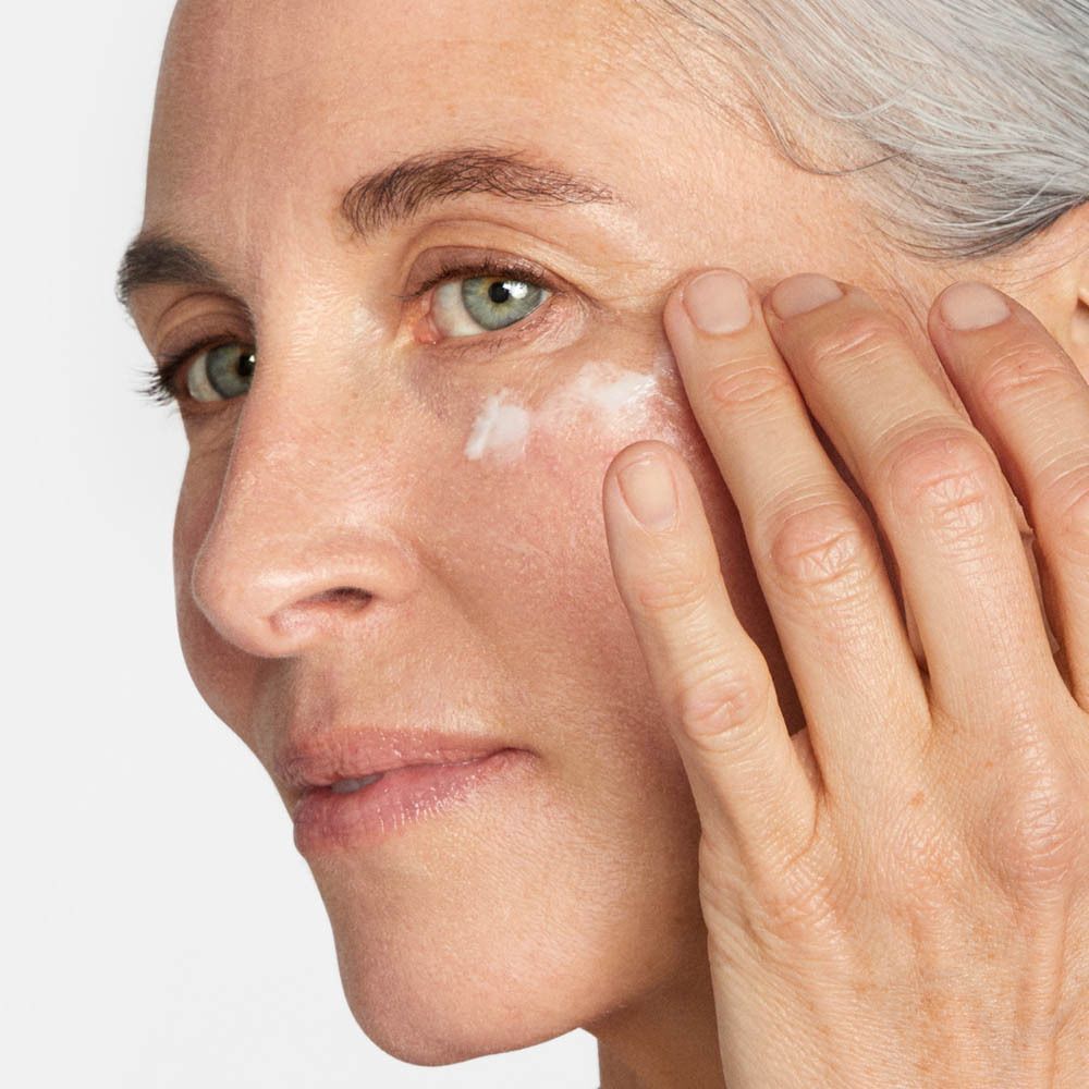 Une femme applique la crème contour des yeux Clinique Smart Clinical Repair.