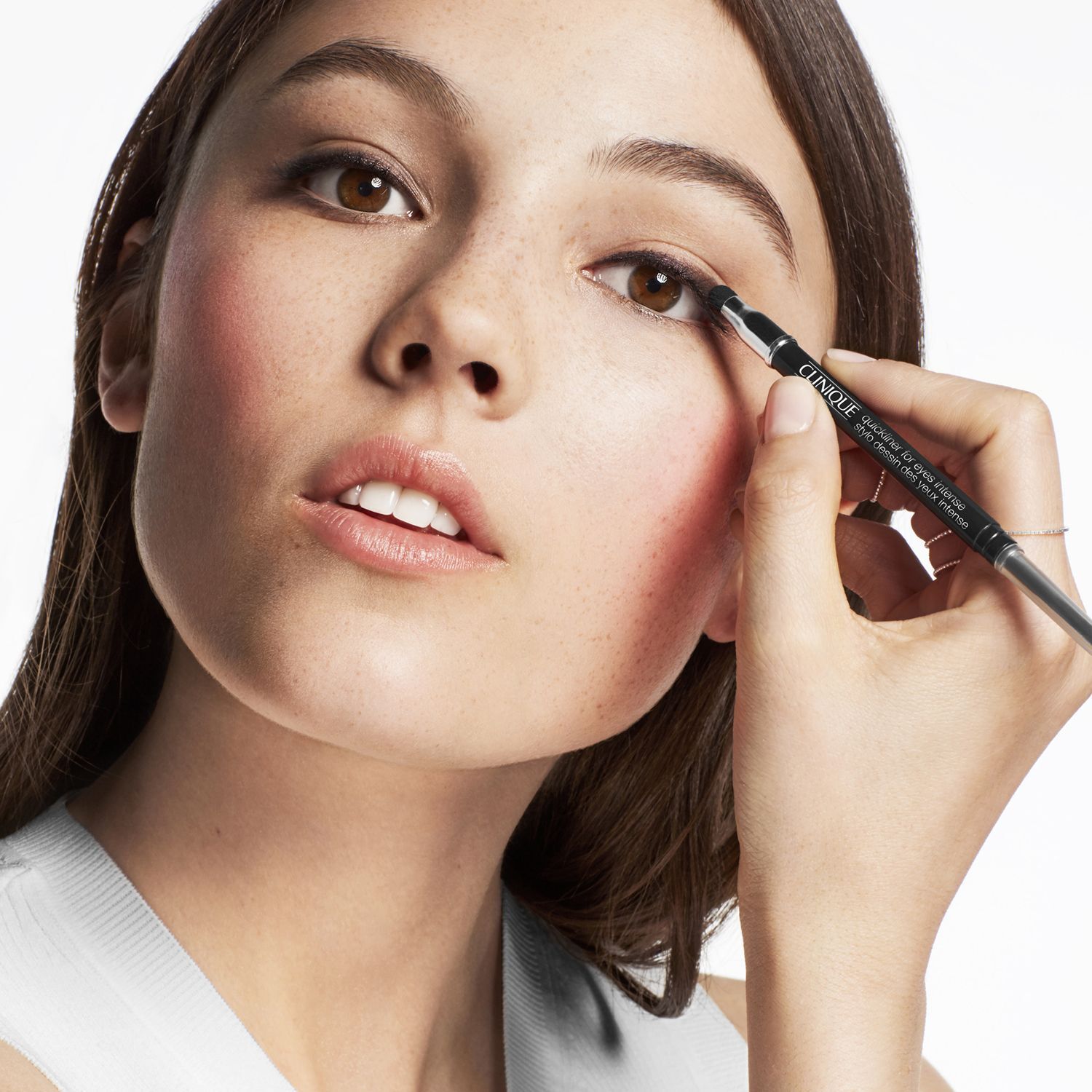 Junge Frau mit Sommersprossen trägt schwarzen Clinique Quickliner™ auf.