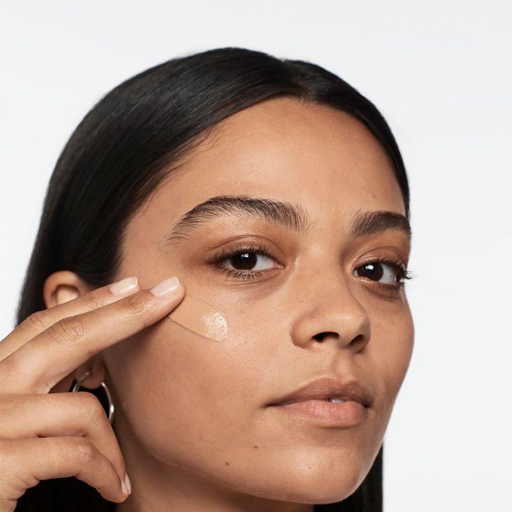 Une femme applique le maquillage liquide CLINIQUE Anti-Blemish Solutions.