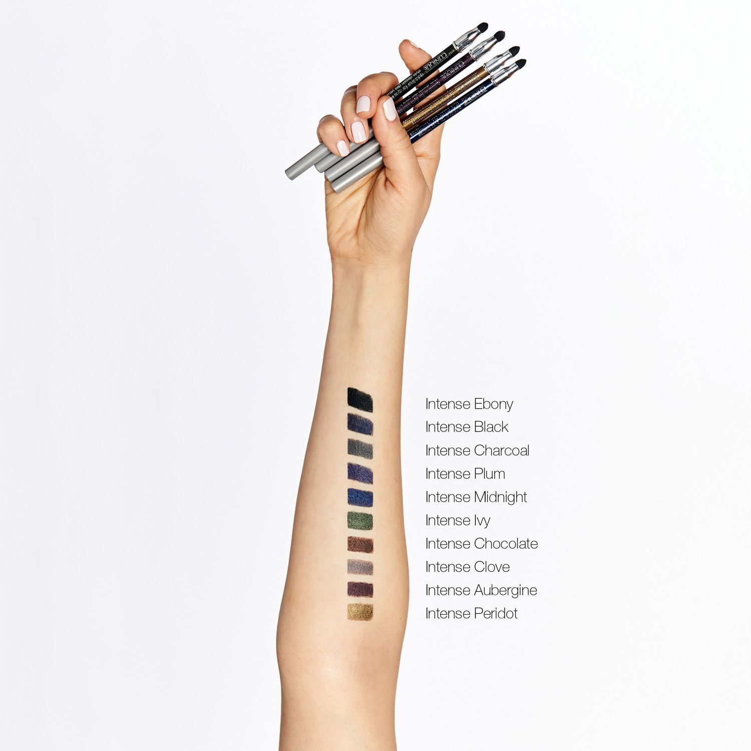 Eine Hand hält mehrere Clinique Quickliner™ Eyeliner. Farbproben sind auf dem Unterarm aufgetragen.