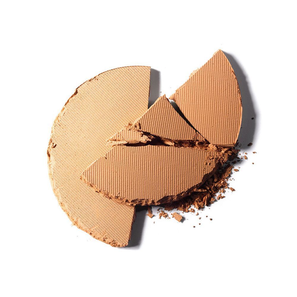 Une poudre beige clair, ronde et rainurée, brisée en plusieurs morceaux.
