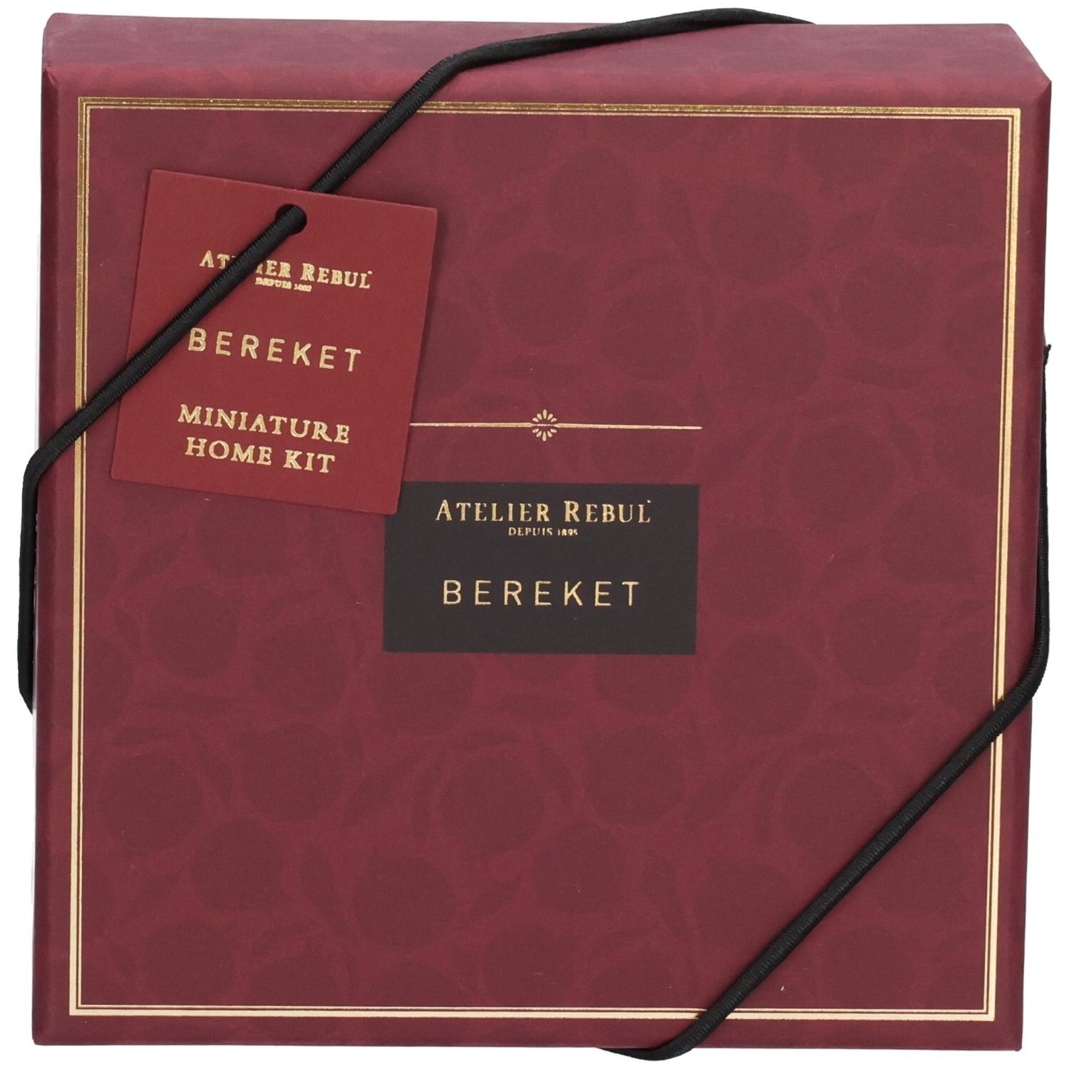 Rote Geschenkbox mit goldfarbenem Rand und schwarzem Band. Anhänger mit Produktnamen und Logo.