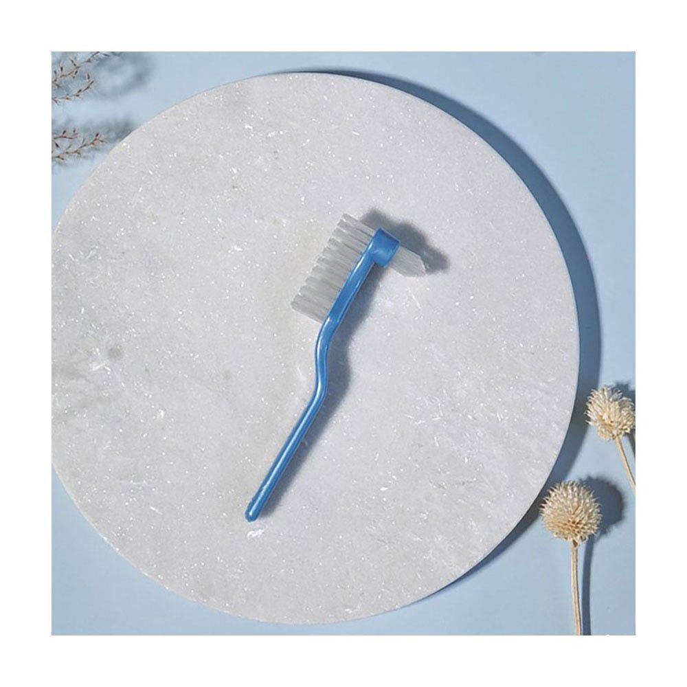 Jordan Clinic Prothesenbürste mit blauem Griff und zweiköpfiger Borste auf weißer Oberfläche.
