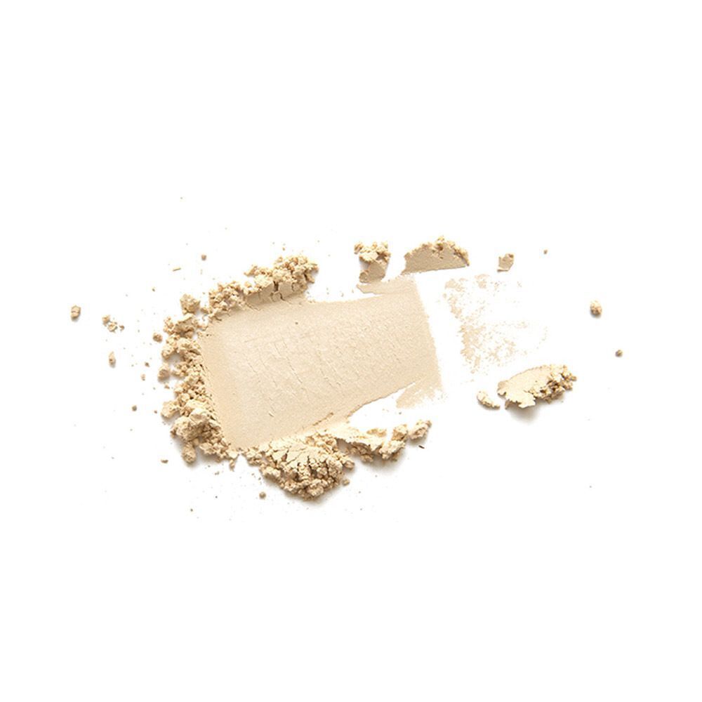 Une touche de poudre minérale beige étalée en texture sur fond blanc.