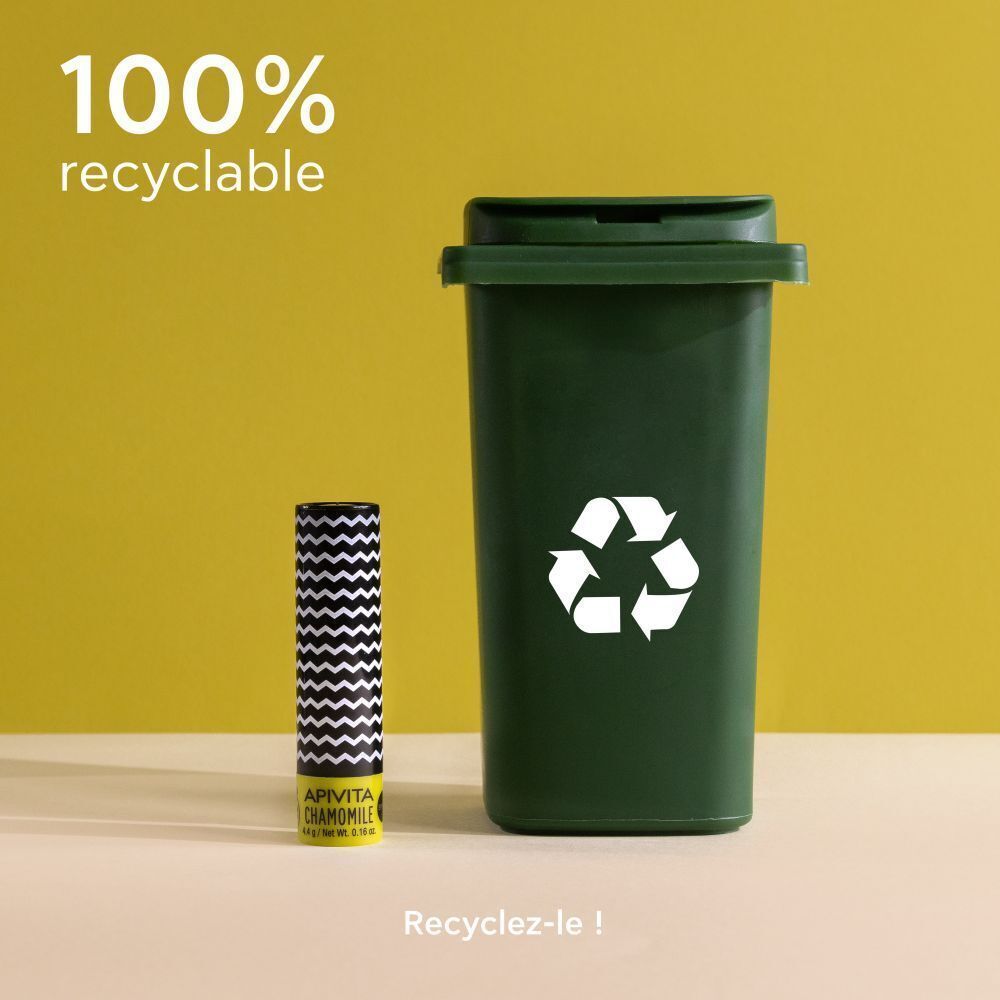 Soin des lèvres à la camomille et SPF15 à côté d'une poubelle de recyclage verte. 100% recyclable.