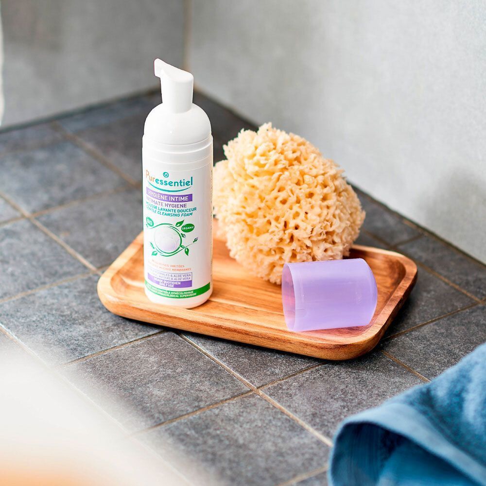 Puressentiel Intimhygiene sanfter Waschschaum auf einem Holztablett mit einem Badeschwamm und Kappe.