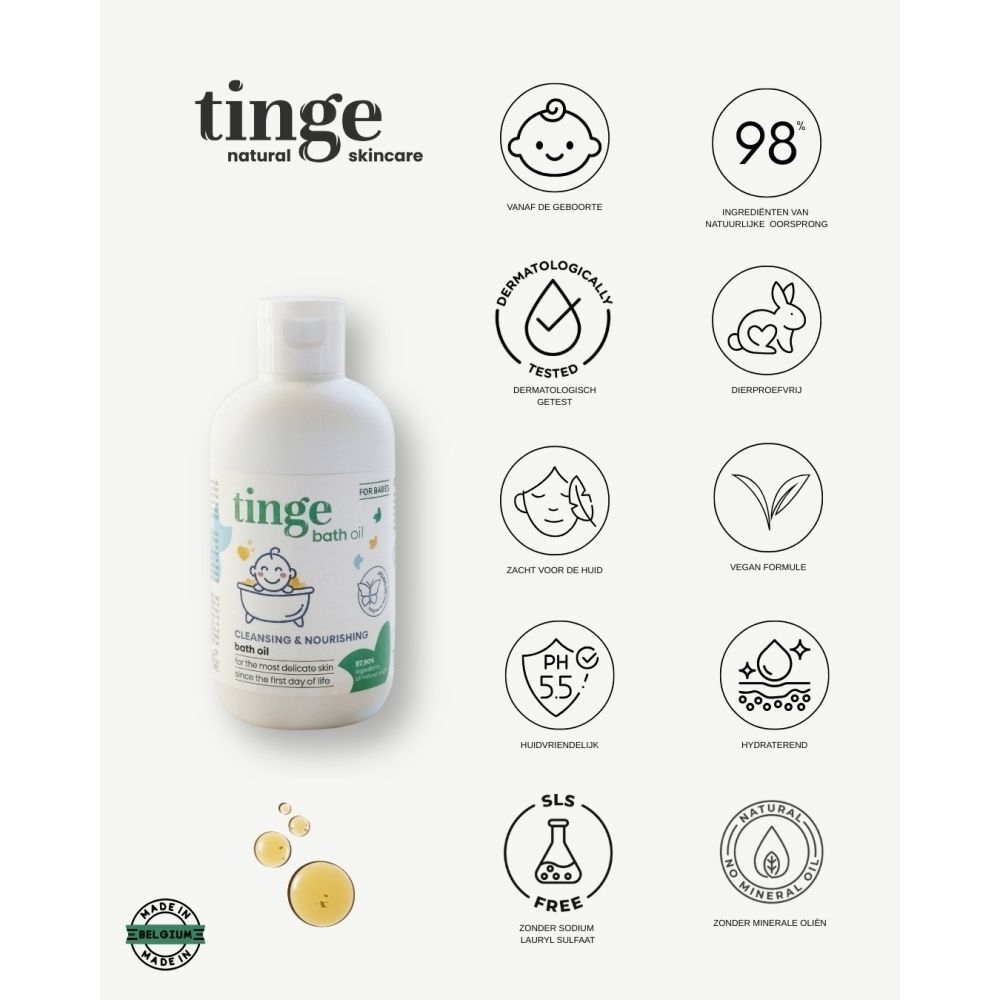 Un flacon d'huile de bain Tinge pour bébés sur une surface en marbre avec quelques gouttes dorées à côté.