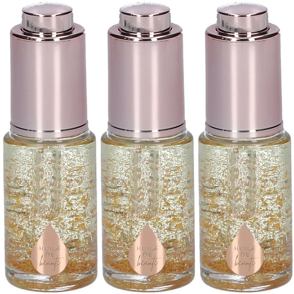 Trois flacons d'huile de beauté avec particules dorées et bouchons roses.