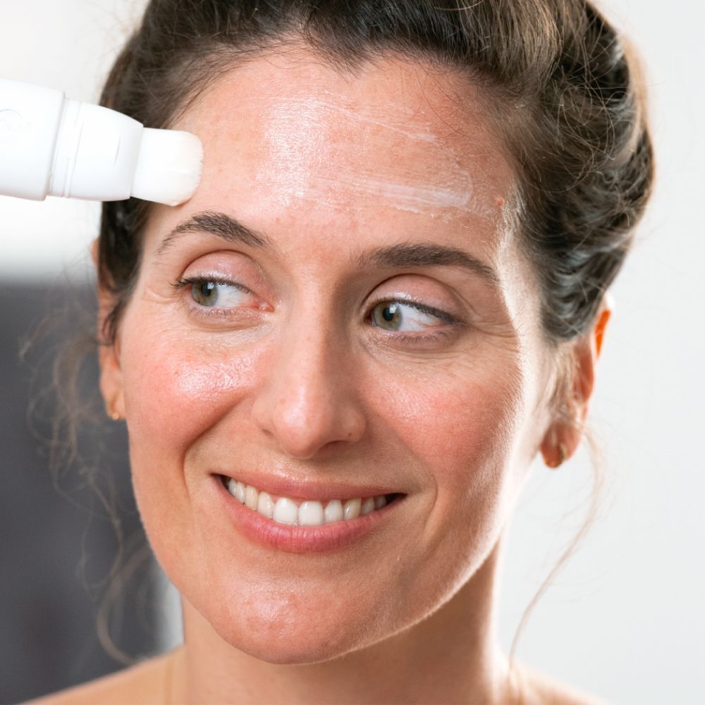 Une femme applique CLAIRIAL Night Peel avec un applicateur sur son front.
