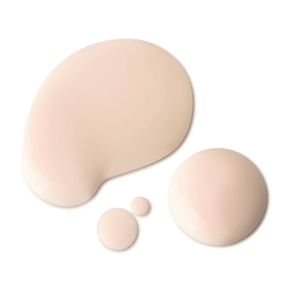 Gouttes d'une lotion beige clair sur fond blanc.