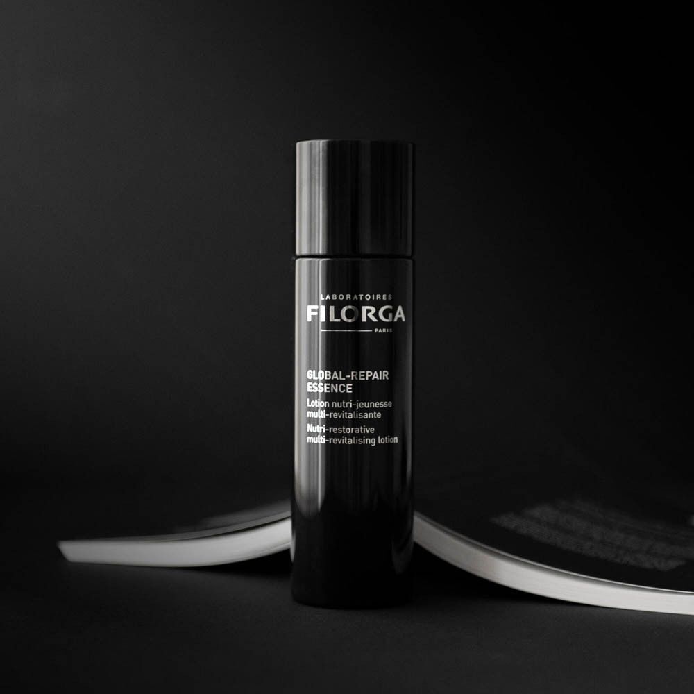 Un flacon noir FILORGA Global-Repair Essenz sur fond sombre.