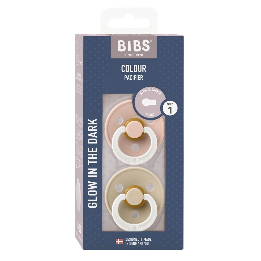 Deux sucettes BIBS Colour, taille 1. Une sucette rose avec tétine jaune, une beige avec anneau blanc.