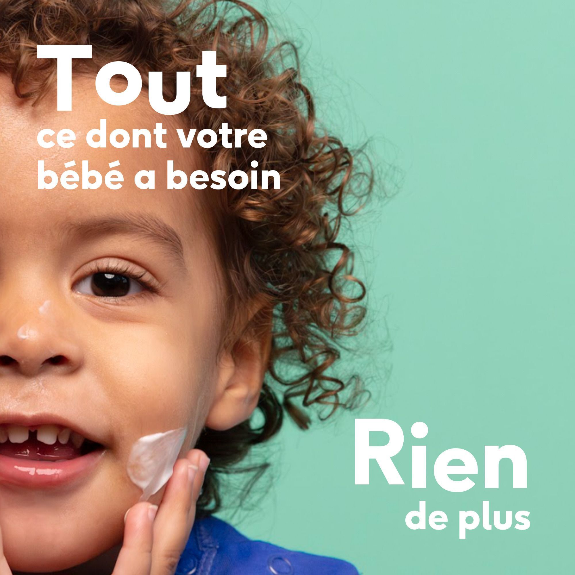 Gros plan d'un bébé souriant recevant de la lotion sur la joue.