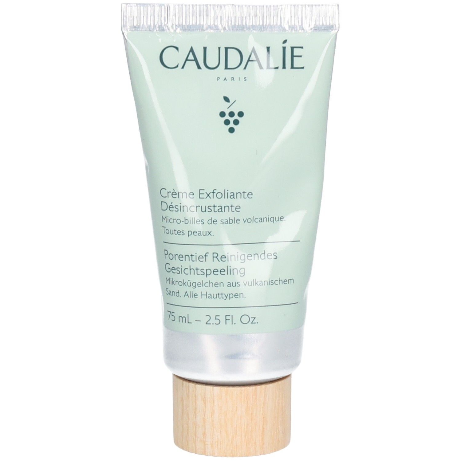 Grüne Tube mit CAUDALÍE-Logo und Produktbezeichnung. Text: Crème Exfoliante Désincrustante, Porentief Reinigendes Gesichtspeeling. Holzfarbener Boden.