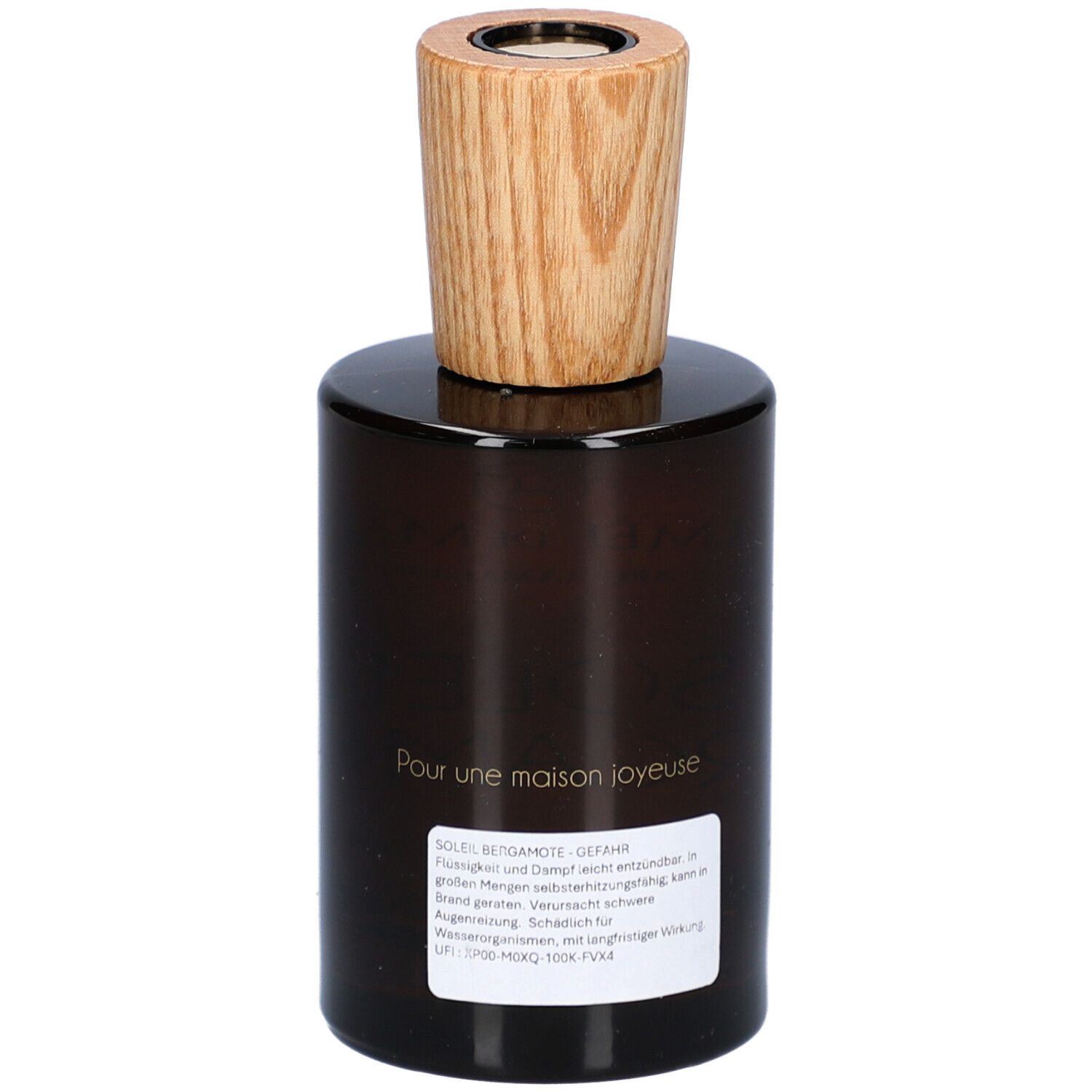 Flacon en verre brun avec bouchon en bois. Étiquette au dos avec texte. Inscription : Pour une maison joyeuse.