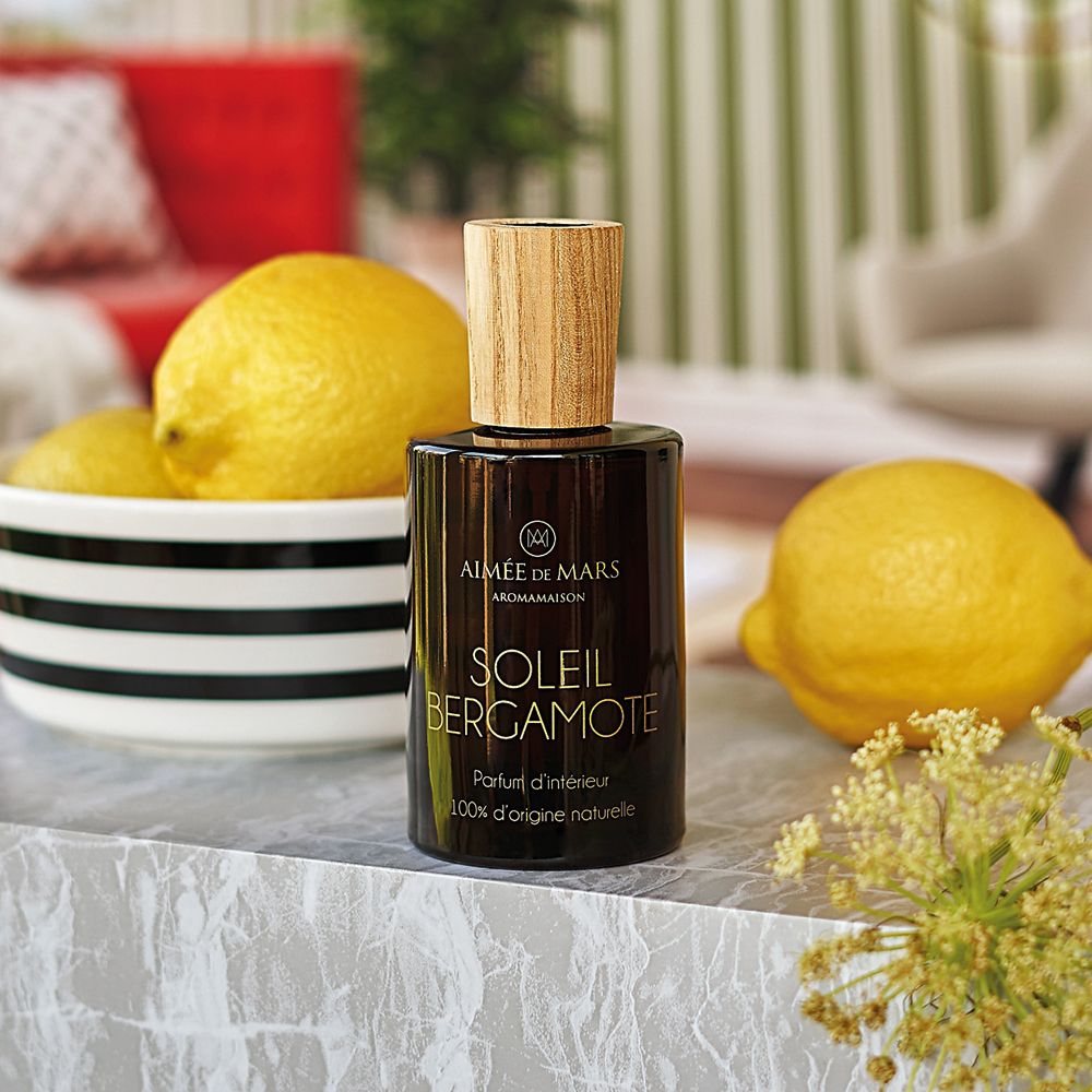 Braune Glasflasche mit Holzdeckel neben Zitronen und einer Schale. Aufschrift: Soleil Bergamote. Marke: Aimée de Mars.