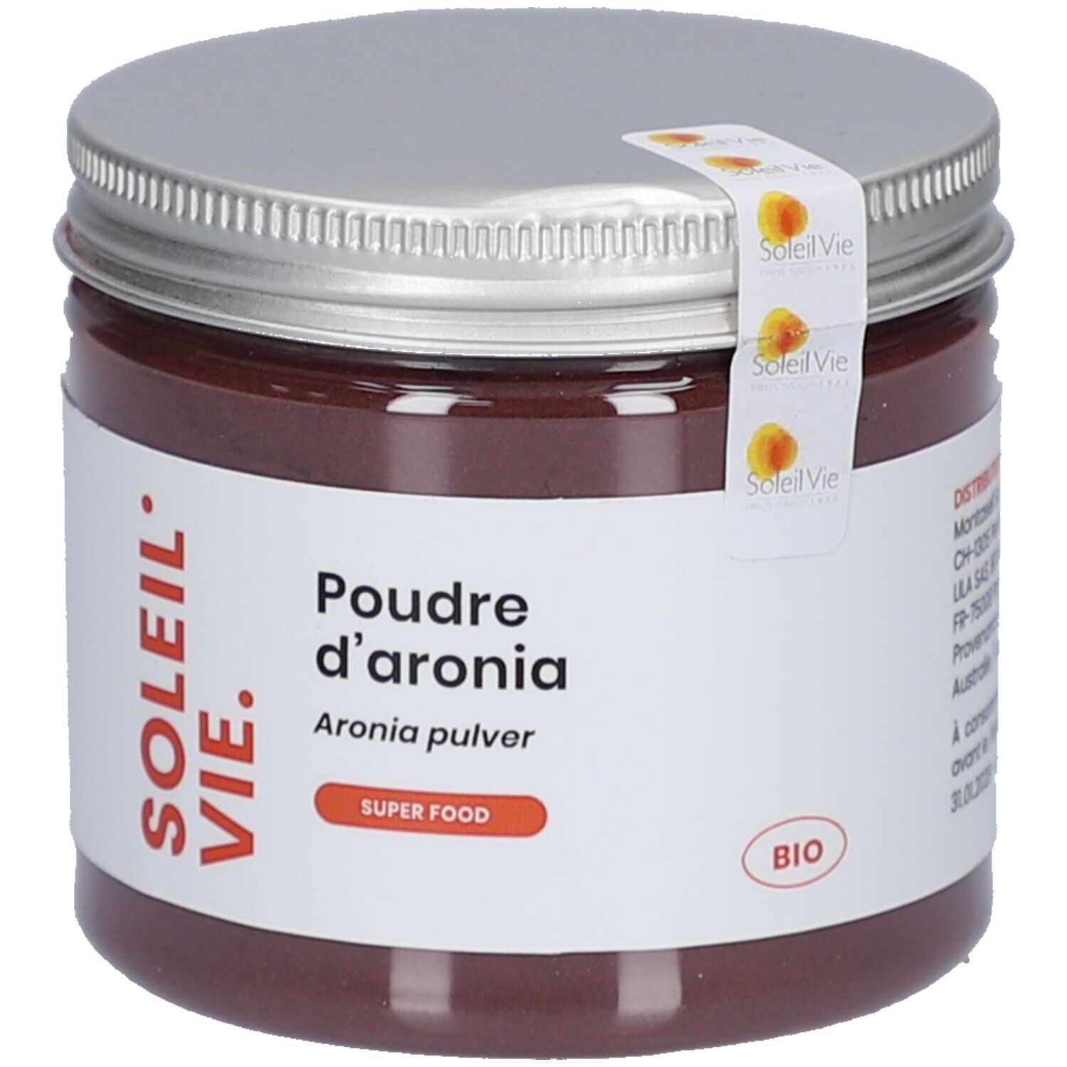 Poudre brune dans un pot en verre avec couvercle argenté. Étiquette avec texte: SOLEIL VIE, Poudre d'aronia, Aronia pulver, BIO. Autocollant avec logo.