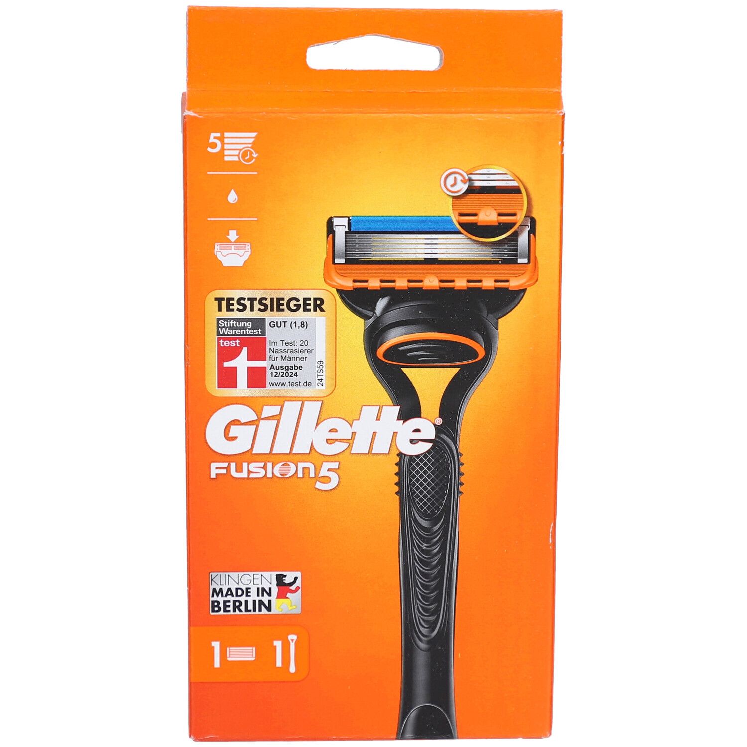 Rasierapparat in orangefarbener Verpackung. Schwarzer Griff, orangefarbener Rasierkopf mit blauer Klinge. Text: Gillette Fusion5, TestSieger.