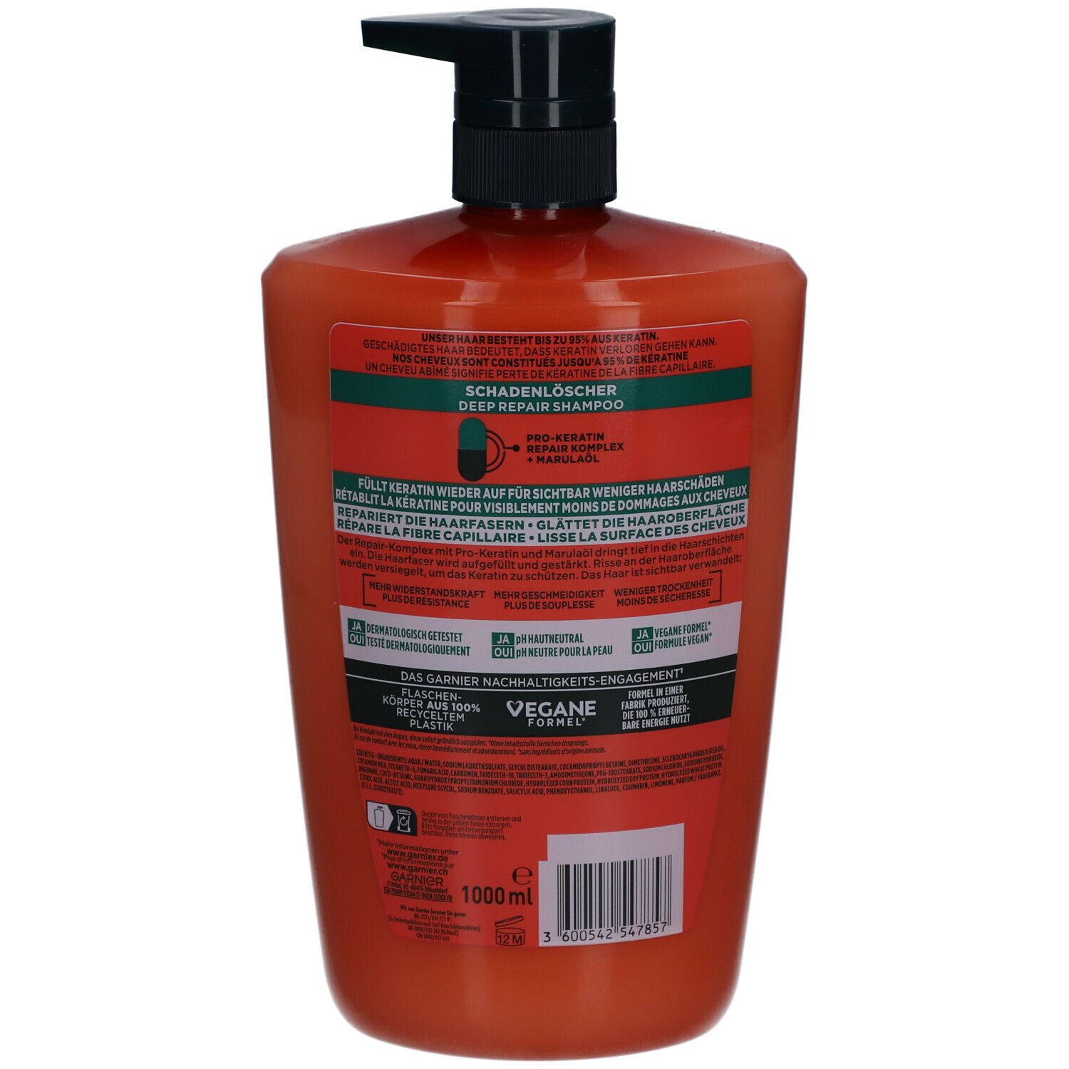 Dos d'un flacon de shampooing orange. Pompe noire. Texte et logos sur l'étiquette.