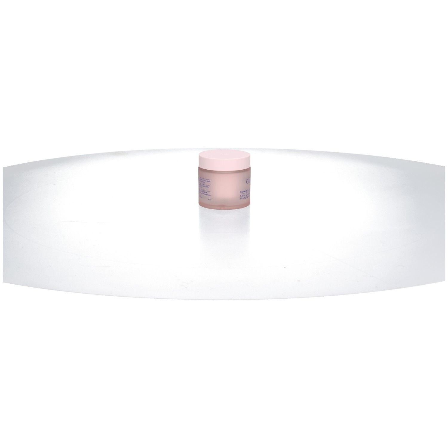 Pot de crème rose sur surface blanche incurvée. Couvercle et nom du produit visibles.