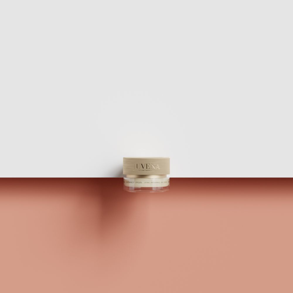 Kleiner Creme-Tiegel mit goldfarbenem Deckel. Aufschrift: Juvena. Auf rotem und weißem Hintergrund platziert.