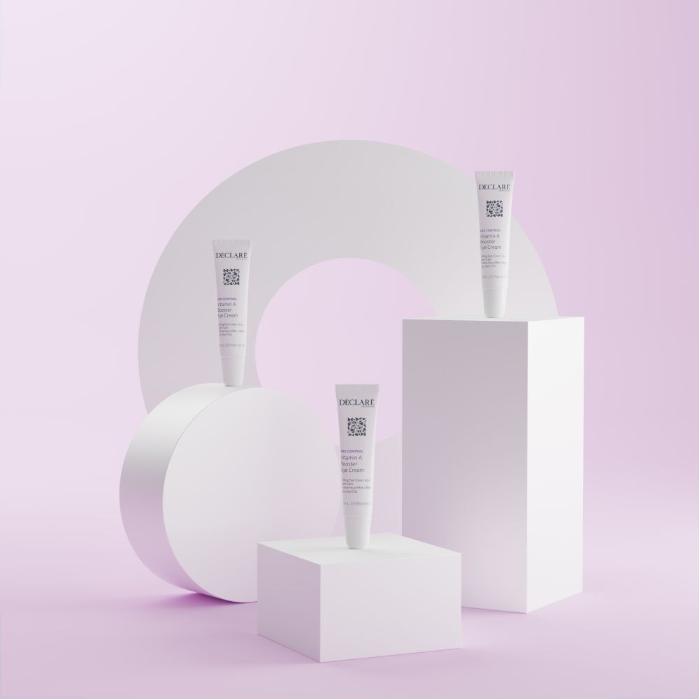Trois tubes DECLARÉ Vitamin A Booster Eye Cream sur socles. Fond: formes géométriques.