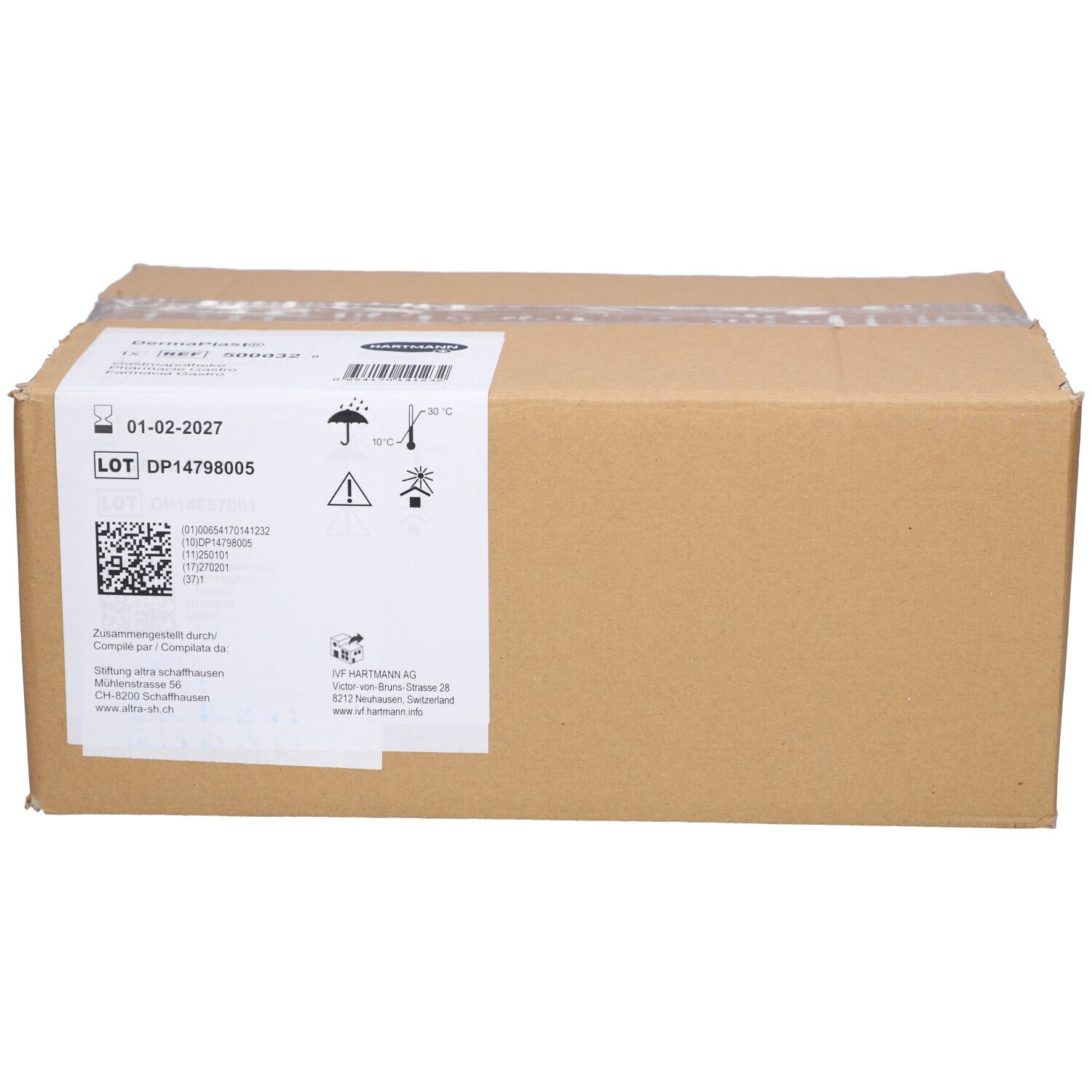 Brauner Karton mit weißem Etikett. Etikett mit Text, Barcode und Symbolen. Klebeband verschließt den Karton.