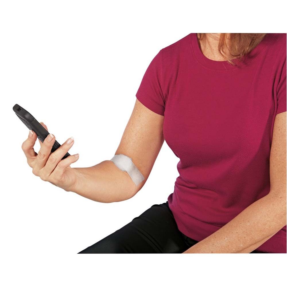 Person mit Pflaster am Arm. Pflaster ist weiß und bedeckt einen Teil des Arms. Person hält Smartphone.