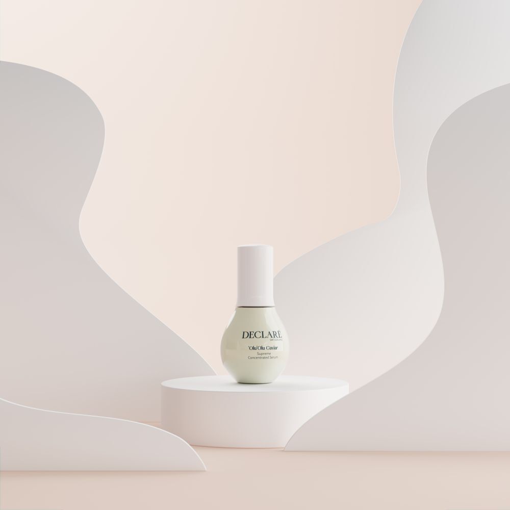Flacon de sérum sur socle. Fond avec formes blanches. Inscription: DECLARÉ, 'Olu 'Olu Caviar, Supreme.